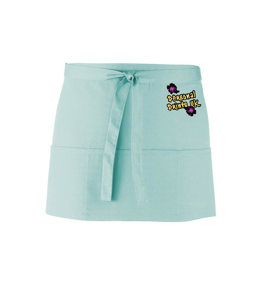 An aqua, short waist apron with 3 pockets and a tie front displaying the Personal Prints UK logo on the top right of the apron.